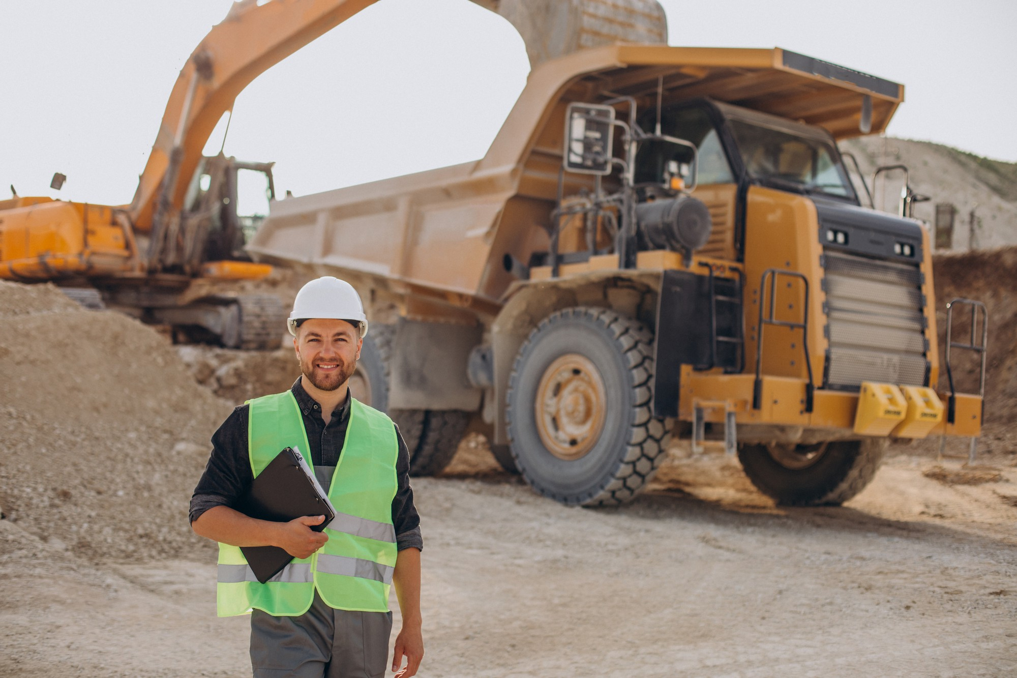 Man standing in front of large dump truck on construction site